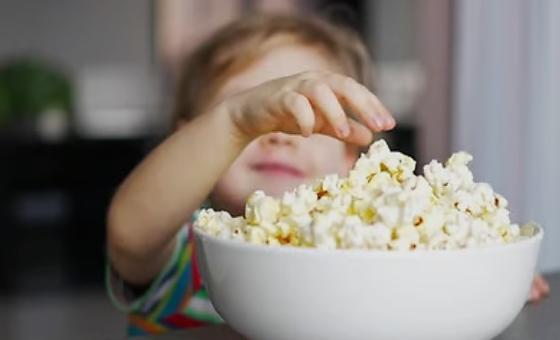 criança comendo pipoca